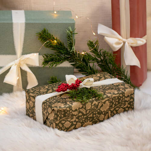 Regali natalizi decorati con rametti di abete, bacche rosse e nastri chiari