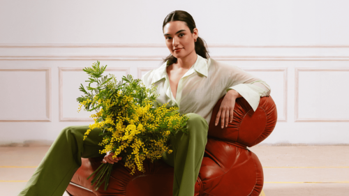 Donna seduta con un bouquet di mimosa tra le braccia in un ambiente elegante