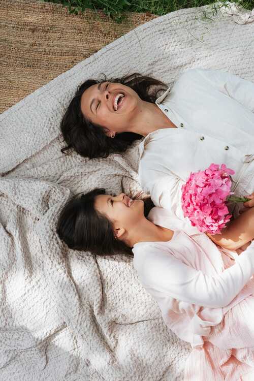 Mamma e figlia sdraiate insieme con un bouquet di fiori rosa
