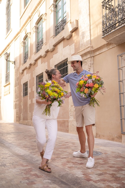 fidanzati camminano felici con in mano bouquet colorati